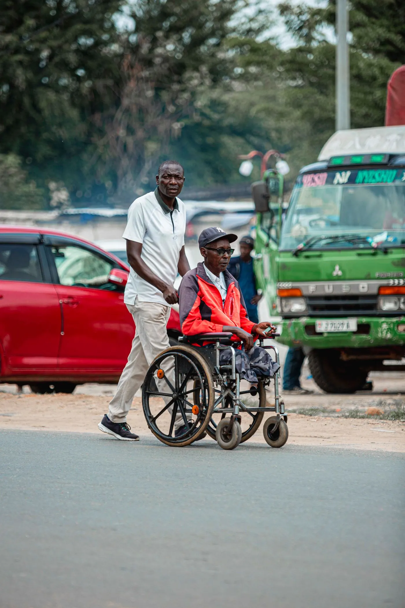 A father pushing his son's wheelchair along a city street