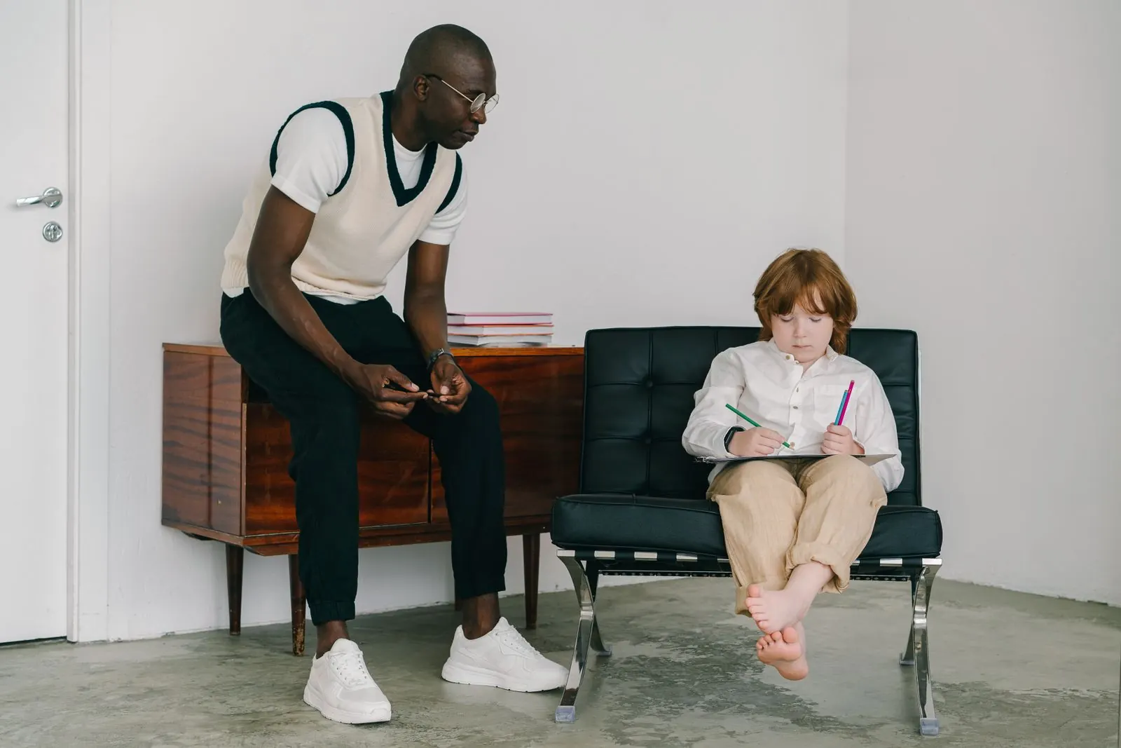 A support professional and a child working through an activity together at a table